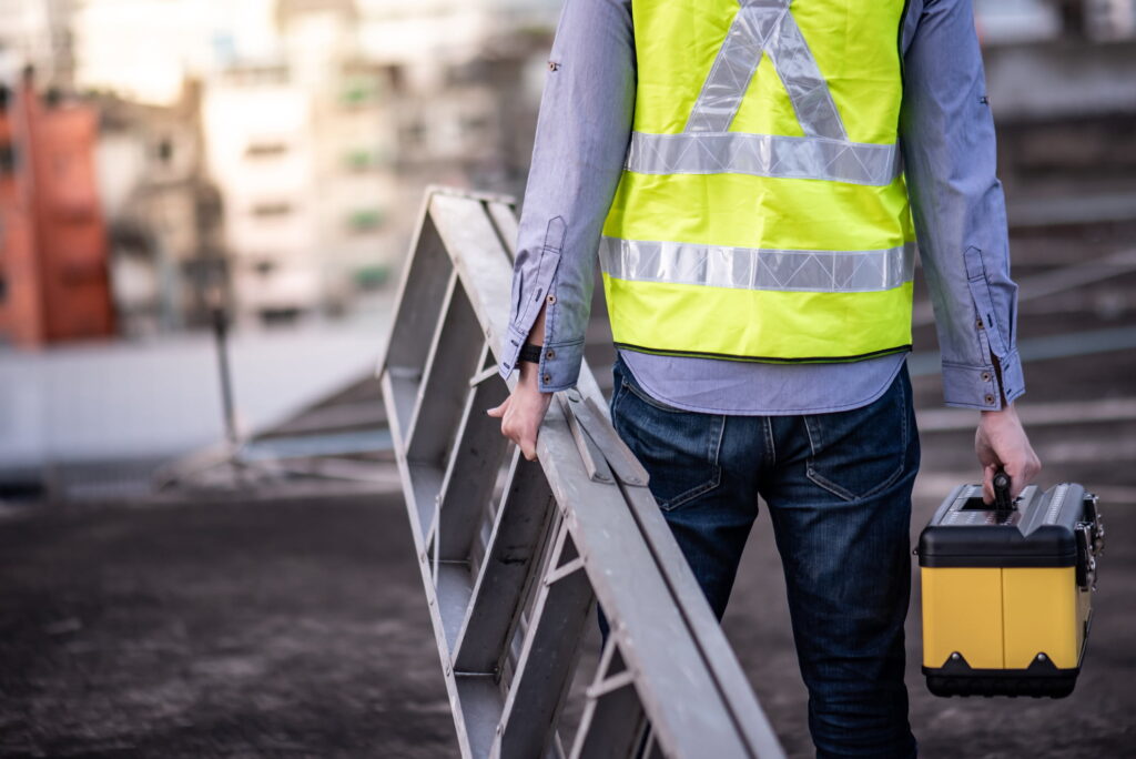 Man carrying ladder in high vis jacket representing importance of ladder safety.